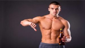 homem musculoso fazendo sinal negativo com uma cerveja na mao