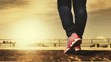 pernas de pessoa caminhando com tênis rosa